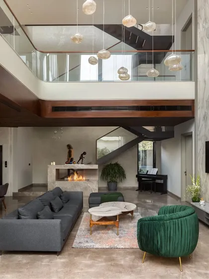 The double-height living space in the APP Residence, featuring a modern fireplace and a dramatic marble accent wall. This image captures the home's blend of cozy comfort and architectural grandeur.
