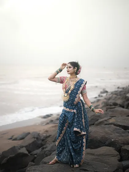 The model posing by the sea, with the waves in the background. The makeup is bold and defined, perfect for this strong look.