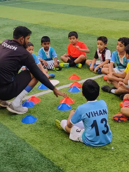 A coach explains a drill to our youngest players using cones. We believe in teaching tactical understanding from the very beginning.