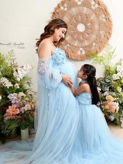A sweet look between mother and daughter. Their matching blue floral gowns and the beautiful floral setup create a soft and dreamy family portrait.