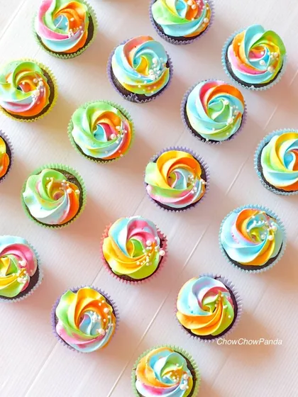 A full view of my rainbow swirl cupcakes. I use multiple colours in the frosting to create this vibrant effect, finishing each one with a sprinkle of edible pearls for a little sparkle.