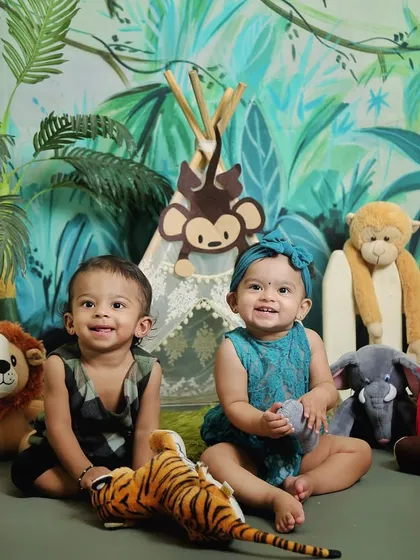 A brother and sister twin duo enjoying their jungle-themed photoshoot. The lush green backdrop and friendly animal props create a fun and wild setting.