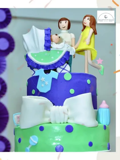 Celebrating a growing family with this custom three-tiered cake. It features adorable fondant figures of the parents and their new baby in a pram, telling a sweet story.