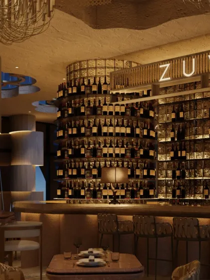 Another view of the sculptural bar at Zuvaah. The cylindrical form, wrapped in rows of wine bottles, creates a powerful focal point, while the warm lighting enhances the intimate, cavernous feel.