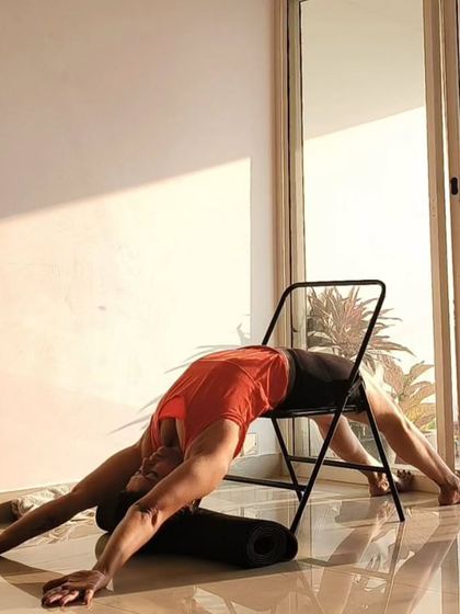 This is a supported Viparita Dandasana using a yoga chair. The chair helps to open the chest and shoulders deeply while fully supporting the spine, making it a powerful restorative backbend.