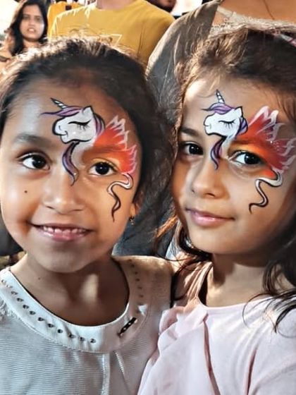 Twinning. Two friends with matching unicorn face paintings, complete with fiery orange wings.