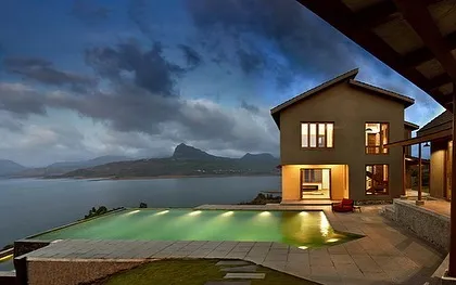 The 5 Element House at dusk, overlooking Pavna Lake. The infinity pool lights up, creating a serene and dramatic effect against the backdrop of the Sahyadri mountains.