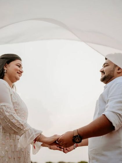A lighthearted and sweet moment with the couple holding hands under a white veil.