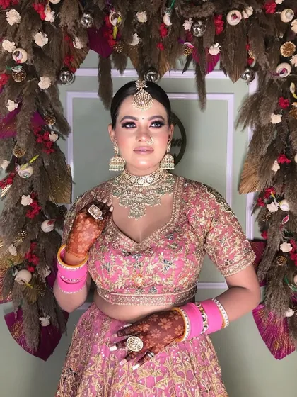 A stunning client ready for a big event. Her pink lehenga is beautifully complemented by the rich color of her mehndi.