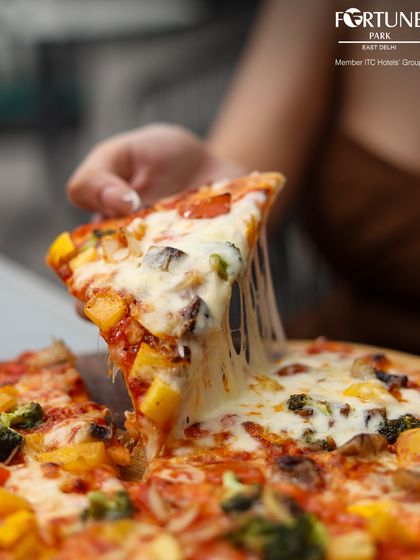 The perfect cheese pull from our wood-fired pizza is a sight to behold. Made with fresh dough and premium toppings, it's a favorite among our guests at Nakshatra.
