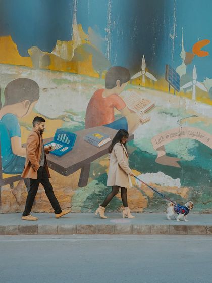 A couple walks their dog past a vibrant street mural, blending their everyday life into their pre-wedding photoshoot. We love incorporating personal elements into our sessions.