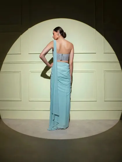 The back view of a powder blue drape saree with a simple, elegant one-shoulder design.