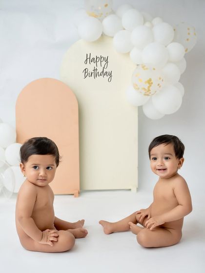 A simple and clean first birthday setup for twins, with a "Happy Birthday" backdrop.
