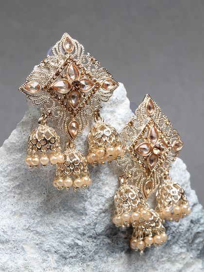 These multi-jhumki earrings feature a diamond-shaped kundan stud and three small pearl jhumkas. They offer a unique silhouette and a beautiful dangling effect.