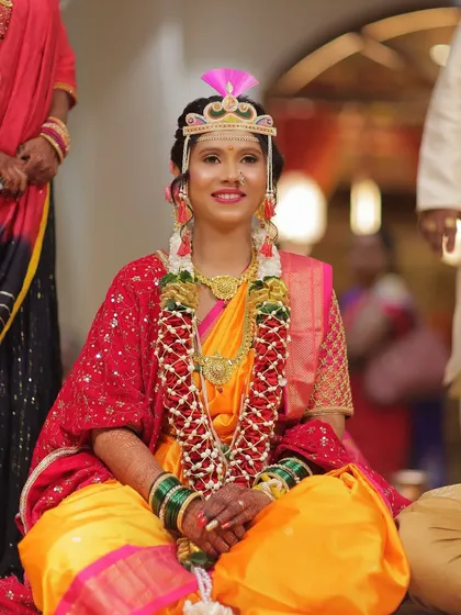 A full-length shot of the bride seated during the ceremony. Her vibrant yellow and pink saree, combined with her radiant makeup, creates a stunning visual.