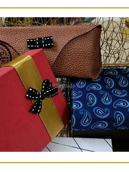 A glimpse of a hamper for him, featuring a paisley tie, a leather-textured pouch, and a gift box, all in a sophisticated color palette.
