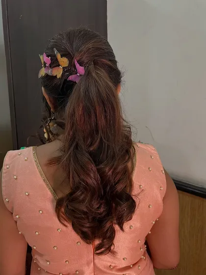 A playful and chic ponytail adorned with colorful butterfly clips. This is a fun and unique hairstyle for a pre-wedding event like a mehendi or carnival.