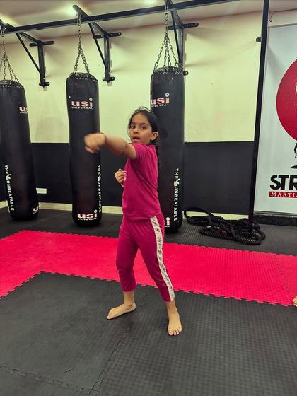 A little striker practices her punching stance. Our classes teach children the fundamentals of martial arts, building a strong base for future growth.