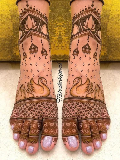 Your bridal look is complete with beautiful feet mehndi. This elegant design features graceful swans and delicate jhumka motifs, ensuring you look perfect from head to toe.
