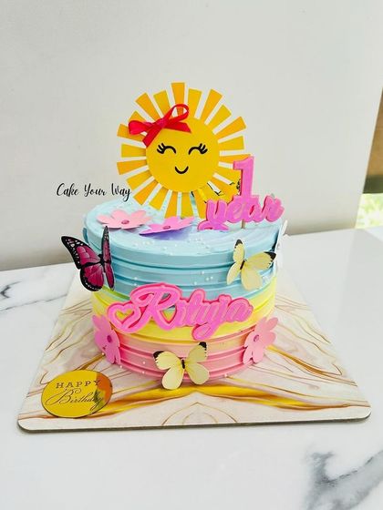 A colorful first birthday cake with a sunshine and butterfly theme, bringing brightness and joy to the celebration.