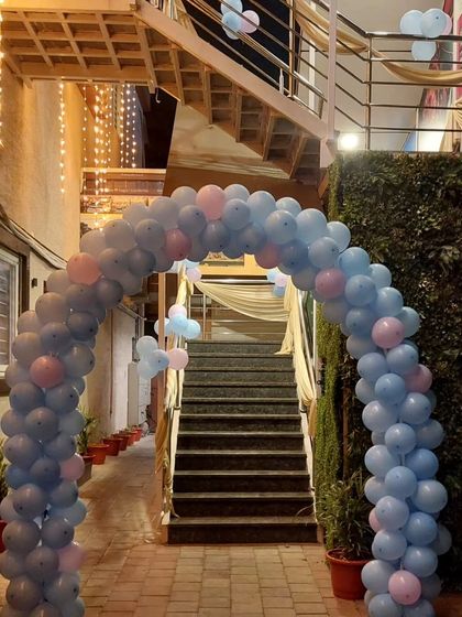 A simple yet effective way to decorate a large entrance or staircase. This long, flowing balloon arch in pastel blue and pink guides guests into the party venue, creating a welcoming and festive atmosphere from the moment they arrive.