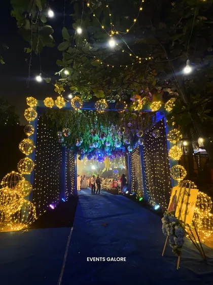 A magical fairy light entrance for a Sangeet night. The archway is adorned with glowing orbs and hanging lights, creating a truly enchanting welcome for guests.