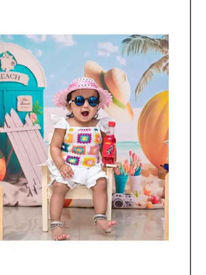 A fun and expressive shot from a beach-themed cake smash session. With a wide-open mouth and stylish sunglasses, this little girl is the star of her birthday celebration.
