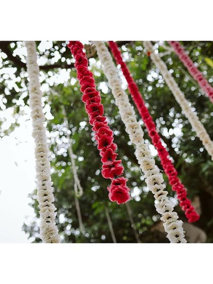 Hanging garlands of white and red flowers add color and texture against the natural green backdrop.