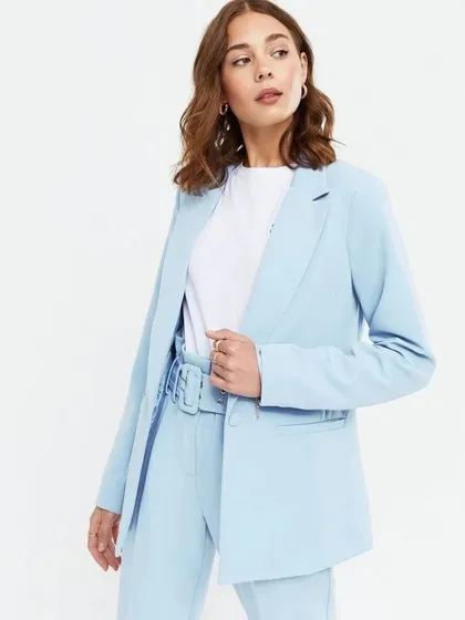 A closer view of the light blue blazer and belted trousers, showing the relaxed fit and comfortable style of this custom suit.