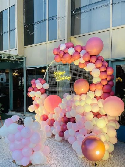 The pink and white balloon setup on an outdoor patio, showing its versatility for different locations.