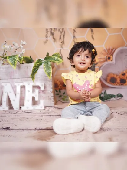 A classic first birthday photo with our light-up 'ONE' sign. The background features a subtle honeycomb pattern and sunflower details, creating a warm and gentle setting.