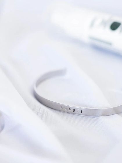 A silver cuff engraved with 'SHRUTI', presented in a bright, clean setting to emphasize its sleek and modern design.