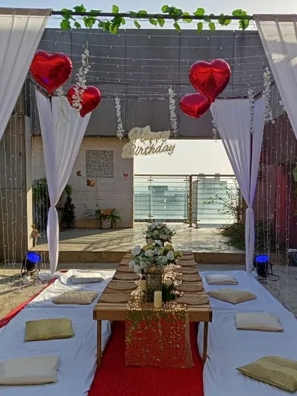 Another view of the rooftop dinner, showing the beautifully arranged table with a floral centerpiece and place settings for an intimate group of friends.