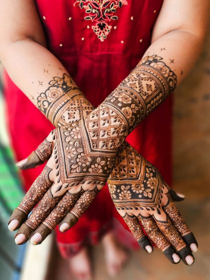 A classic bridal design with geometric patterns on the back of the hands and floral bands on the arms.