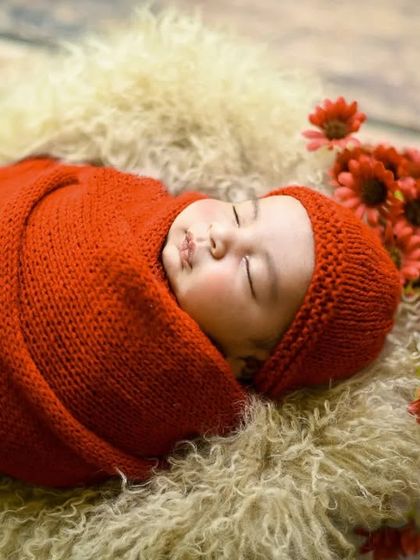An angled shot of the baby in the red knit wrap, showing the soft texture of the fur lining in the basket.