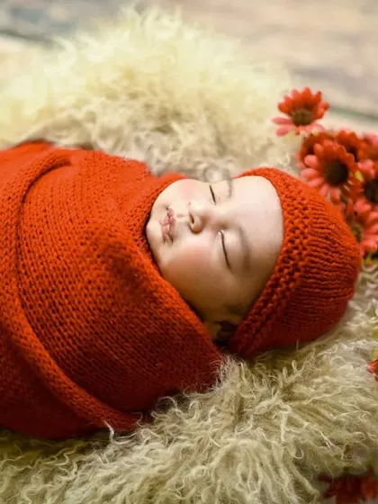 An angled shot of the baby in the red knit wrap, showing the soft texture of the fur lining in the basket.