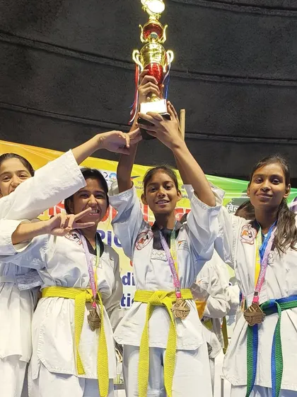 Our female fighters celebrating a team victory, holding up the trophy together.
