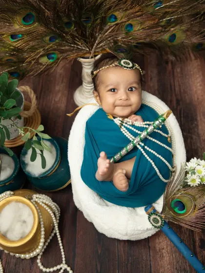 A sweet smile from a little one dressed for Janmashtami. I use soft lighting and props like pearl necklaces and peacock feathers to create a rich, detailed portrait.