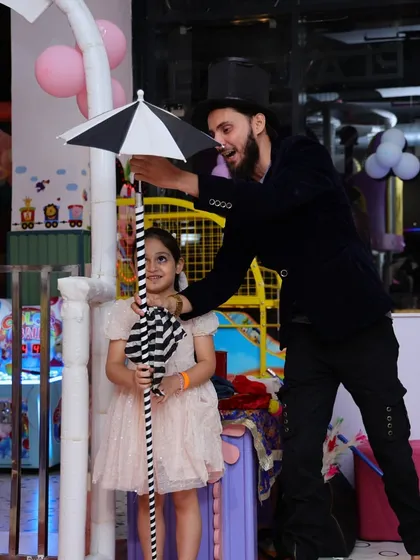 A young girl assists the magician with a trick during her Unicorn Island themed birthday party.