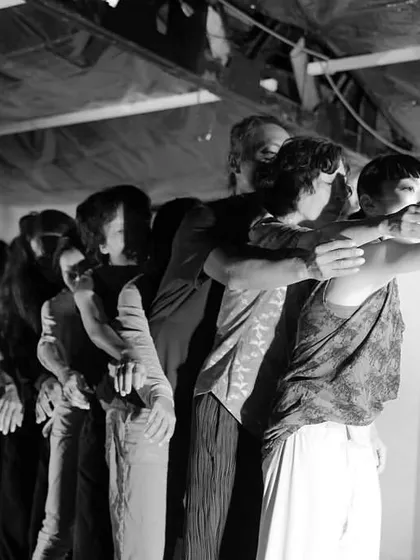 A black and white photo of the "Asia meets Asia" ensemble during the 2022 performance "Still Drifting." The image captures a moment of unity and surrender.
