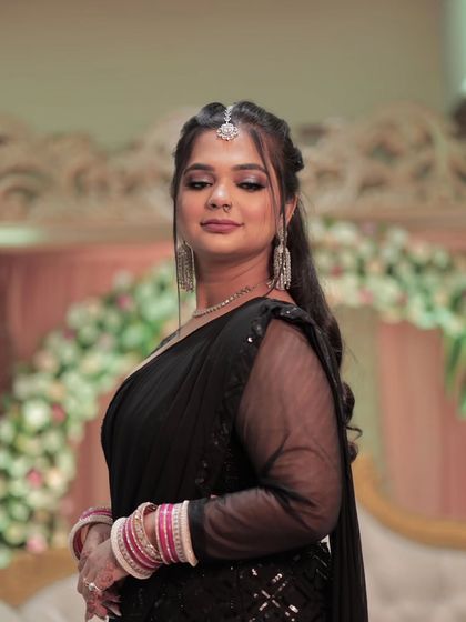 A modern reception look with a touch of drama. This bride's black saree is paired with a glamorous smokey eye, long silver earrings, and a chic ponytail.