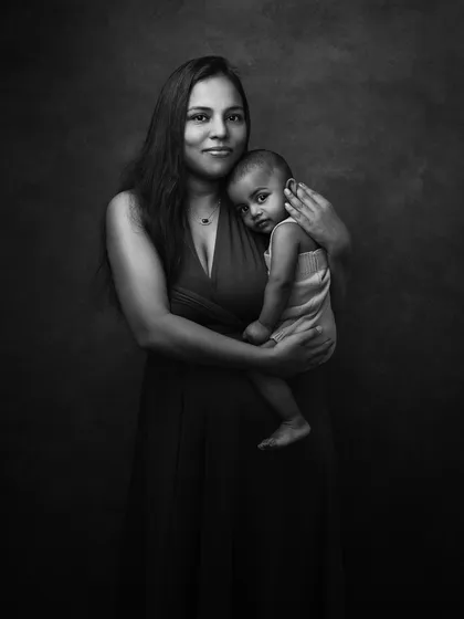 A classic black and white family portrait. The simple composition and beautiful lighting create a timeless image that focuses purely on the connection between mother and child.