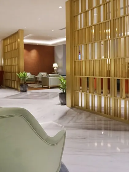 A view across the main lounge at Bangalore airport, showing the brass metal screen that partitions the space. This element adds a touch of glamour and helps to define different zones without closing off the area entirely.