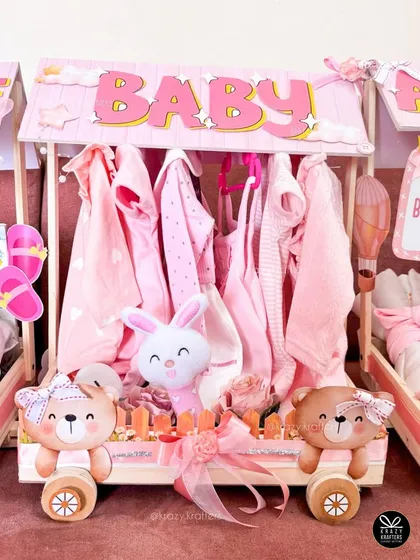 This carriage was designed as a mini closet, with tiny pink baby clothes hung neatly inside. It's a creative and practical way to gift newborn apparel.