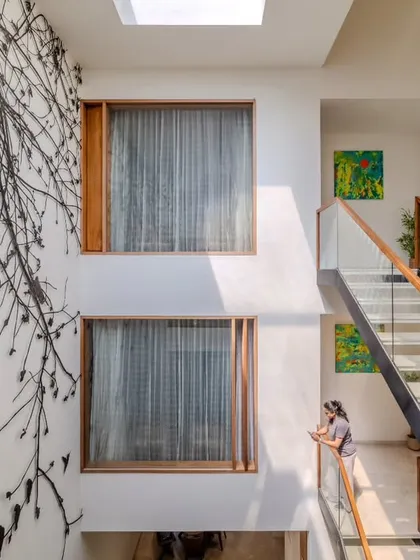 The staircase and the 'Tree of Life' metal artwork are designed to be viewed together. The natural light from the skylight above illuminates both, creating a dramatic and artistic core that is visible from multiple points within the villa.