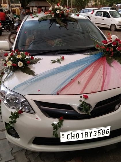 A Toyota Corolla decorated with red and blue fabric drapes and small rose bouquets. This is a simple and elegant design for a classic sedan.
