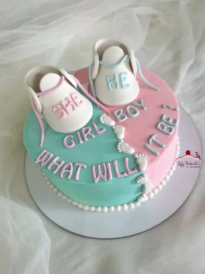 He or she? What will it be? A cute gender reveal cake in a heart shape, split between pink and blue, with adorable baby booties on top.