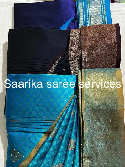 A collection of blue, black, and teal sarees, all professionally folded.