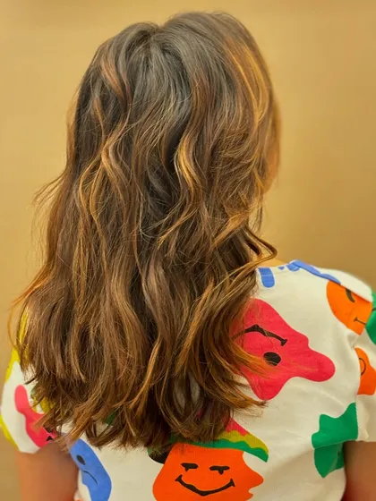 The back of a medium-length haircut with subtle, beachy waves and sun-kissed highlights, creating a relaxed and stylish vibe.