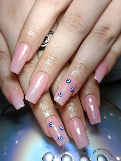 A more subtle take on the evil eye trend, with tiny, hand-painted designs on a natural pink acrylic base.
